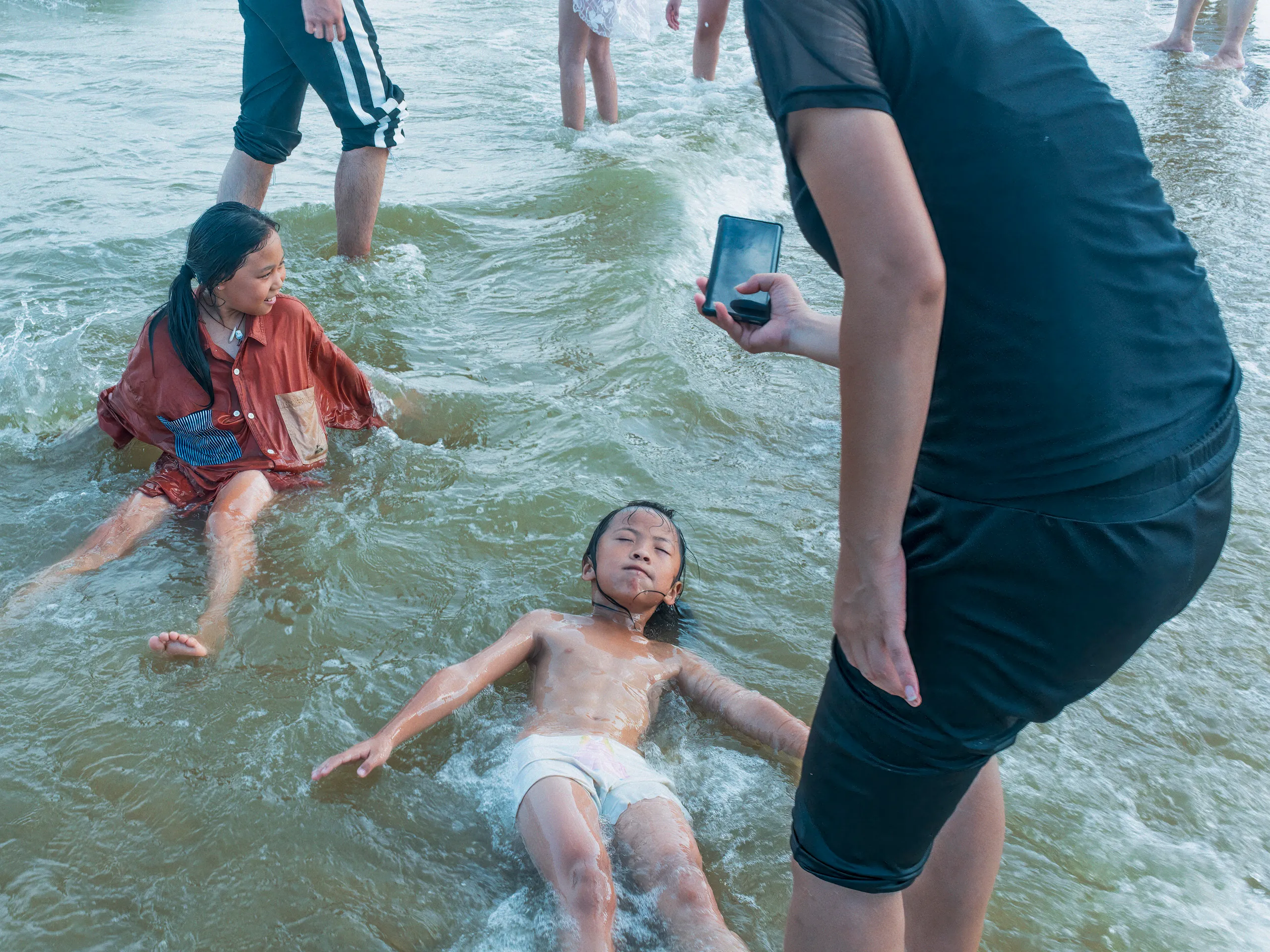 The Strip: Staying Afloat — swimming in the sea off Xiamen beach, photograph by Andras Ikladi